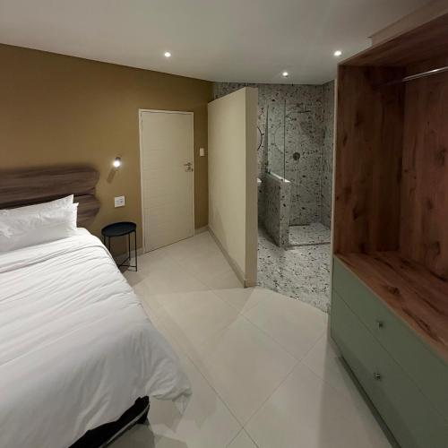 a bedroom with a bed and a bathroom with a shower at Thatch Haven in Mahikeng