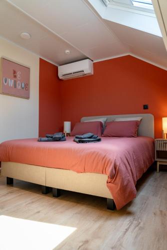 a bedroom with a large bed with an orange wall at L'aparté in Rochefort
