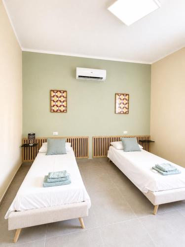 two beds in a room with two windows at Dimora San Francesco in Sarzana