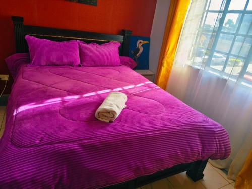a pink bed with a towel laying on it at Greatwall Apartment in Syokimau