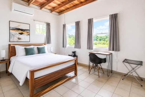 a bedroom with a bed and a desk and windows at Alma Vida Hotel in Manuel Antonio