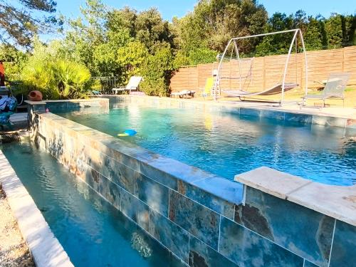 a swimming pool with a stone retaining wall and a swing at Etage privatif chez Corinne in Russan