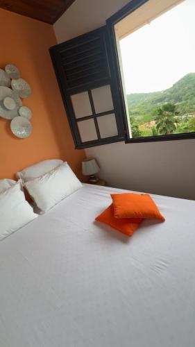 a bedroom with a large white bed with a window at Kéra Lodge in Rivière-Pilote