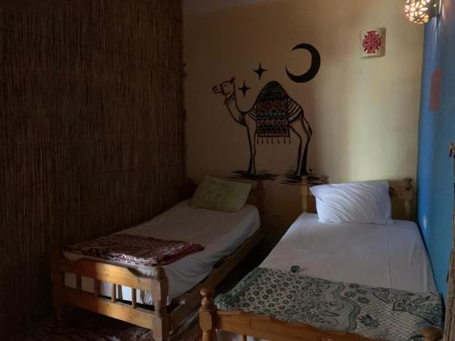 a room with two beds and a camel sticker on the wall at kalima camp in Nuweiba‘ el Muzeinah