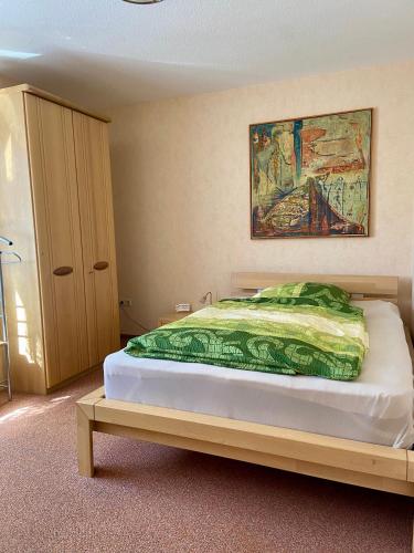 a bedroom with a bed with a painting on the wall at B&B Pension-Schönheim in Monzingen