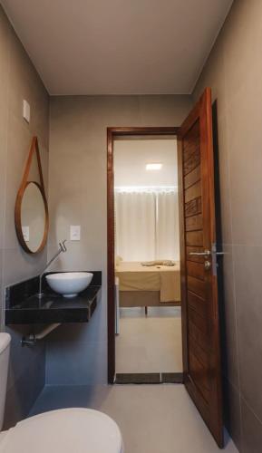 a bathroom with a sink and a toilet and a mirror at Atins Ville Lençóis in Atins