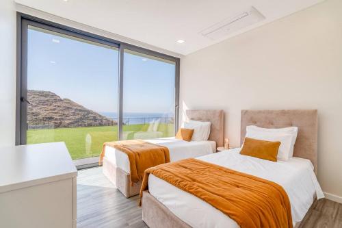 two beds in a room with a large window at Luna Villa in Campanário