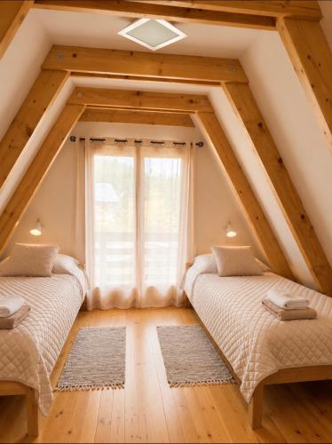 two beds in a attic room with a window at Holiday Home Stefani Spacious Mountain House near Durmitor 3 Bedrooms Private Parking in Žabljak
