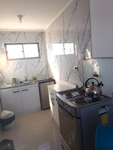 a kitchen with a stove with a tea kettle on it at Cabaña Litueche in Los Manantiales