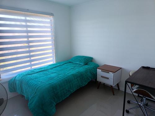 a bedroom with a bed and a desk and a window at Cabaña Litueche in Los Manantiales