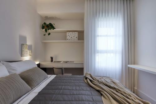 a bedroom with a bed with a desk and a window at Luggo Inter Residence - Região Central BH in Belo Horizonte