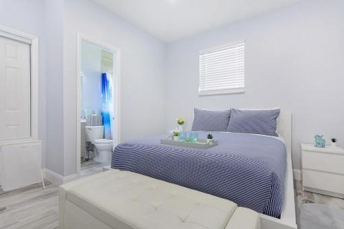 a white bedroom with a bed and a bathroom at Mayas Blue Lagoon Luxury Suite #2 in Fort Lauderdale