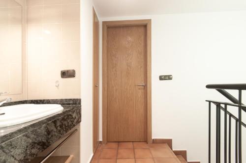 a bathroom with a wooden door and a sink at Apartaments VM Molleres in Soldeu