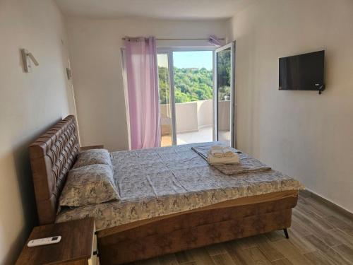a bedroom with a large bed and a sliding glass door at Apartmani Zara in Pečurice