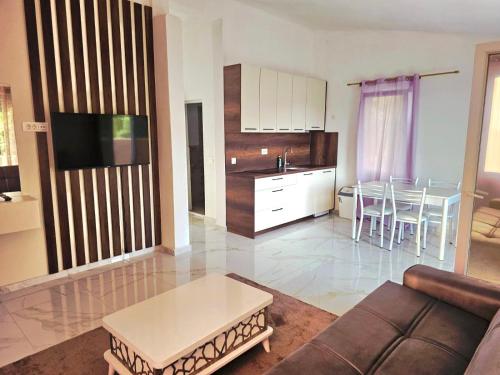 a living room with a couch and a table and a kitchen at Apartmani Zara in Pečurice
