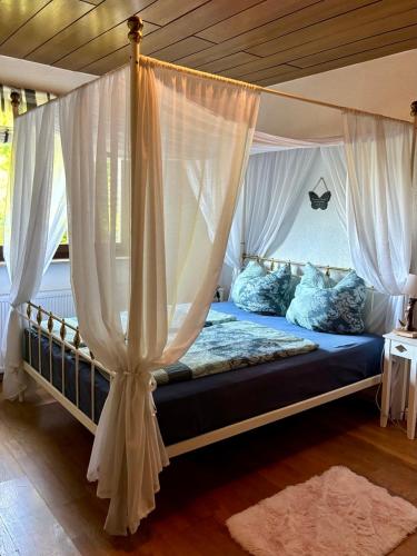 a bedroom with a canopy bed with white curtains at Amselhof Kördorf in Kördorf