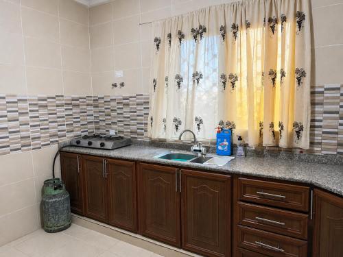 a kitchen with a sink and a window with curtains at جرش in Dayr al Līyāt
