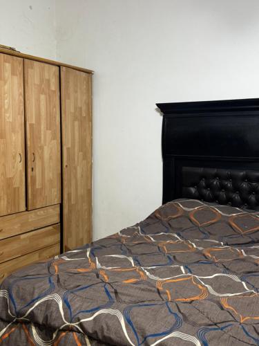 a bedroom with a bed and a wooden cabinet at جرش in Dayr al Līyāt