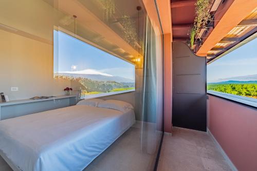 a bedroom with a bed and a large window at Elgio' Design Retreat with Etna View Taormina in Taormina