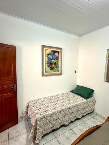 a bedroom with a bed and a painting on the wall at Casa central, com 2 quartos e até 2 carros in Divinópolis