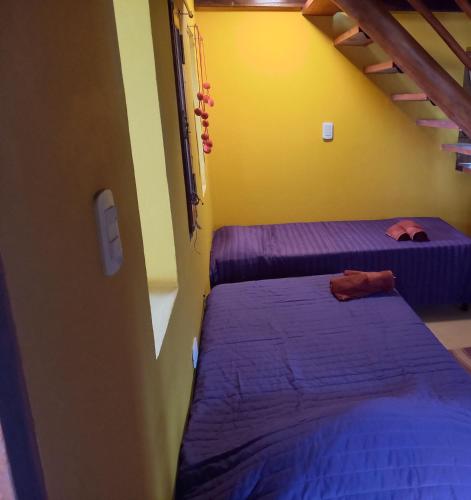 two beds in a room with purple sheets at Luminares in Humahuaca