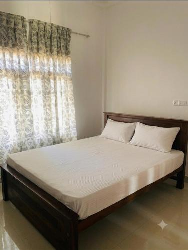 a bed in a bedroom with a large window at Sanku guest house in Jaffna