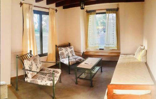 a room with a bed and chairs and windows at Cabañas ConSentidos in Villa General Belgrano