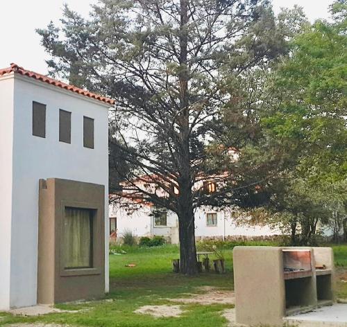 a white building with a tree in the yard at Cabañas ConSentidos in Villa General Belgrano