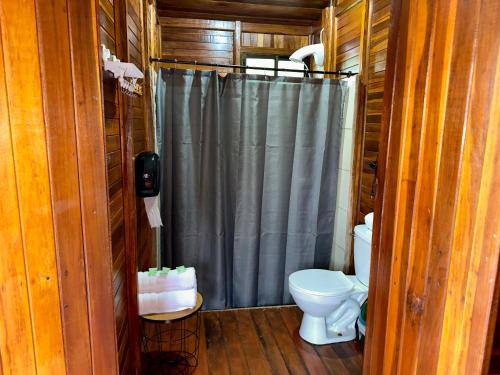 a bathroom with a shower curtain and a toilet at Cabañas Los Laguitos Rio Celeste in El Achiote