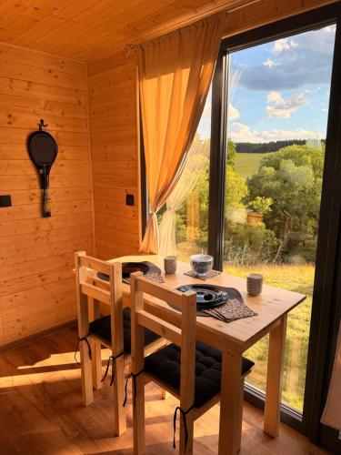 a wooden table and chairs in a room with a window at Maringotka na kopečku in Kotaneč