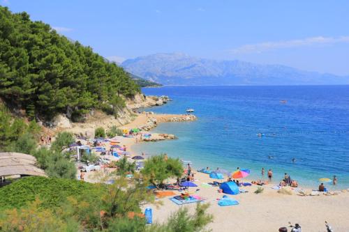 a beach with a bunch of people in the water at White Cove Apartments in Lokva Rogoznica