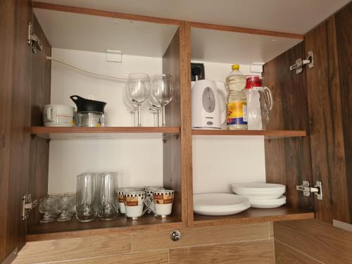 a cupboard with glasses and plates and wine glasses at Milmari N2 Erdeg in Kopaonik