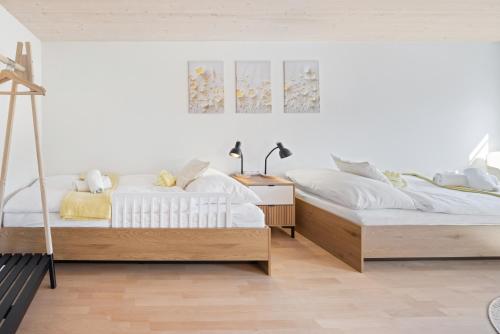 two beds in a room with white walls and wooden floors at BASEKAMP Prime I Friends I Lake I Mountains I Luzern in Küssnacht