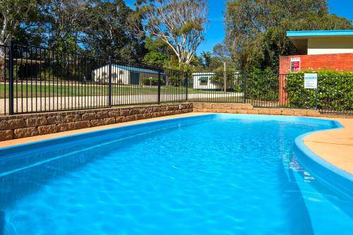 a swimming pool with blue water and a fence at Flynns Beach Caravan Park in Port Macquarie