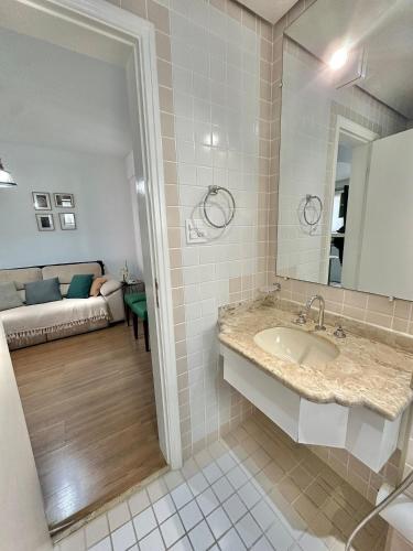 a bathroom with a sink and a mirror and a couch at Flat Funchal JK Limpeza Diária, Internet 300mb in São Paulo