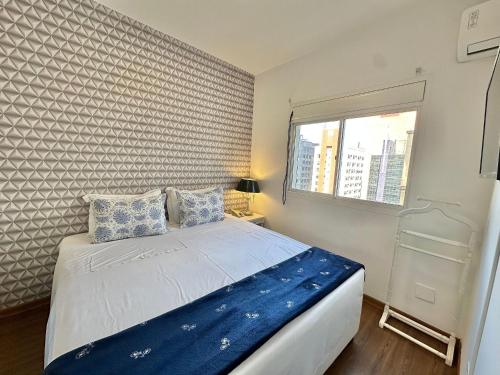 a bedroom with a bed with blue sheets and a window at Flat Funchal JK Limpeza Diária, Internet 300mb in São Paulo