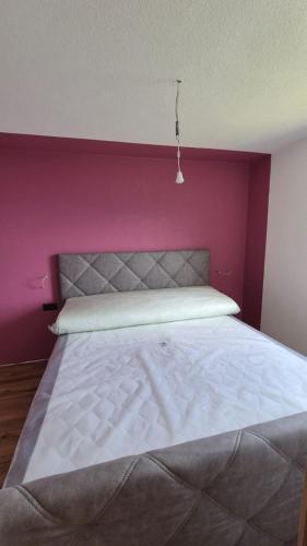 a bedroom with a white bed with a pink wall at Hof am Berg in Kaunerberg