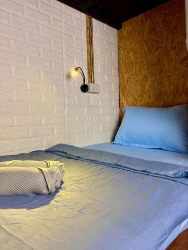 a bed in a room next to a brick wall at Crew Bangkok Hostel in Bangkok