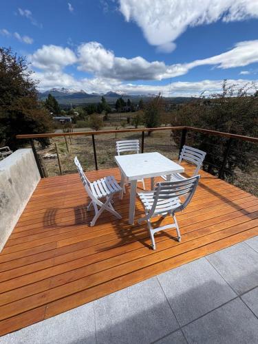 a wooden deck with a table and chairs on it at Complejo Aiken in Trevelín