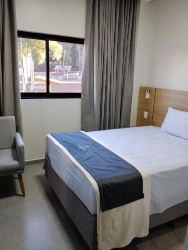 a bedroom with a bed and a chair and a window at Hotel do Catarina in Rio Bonito