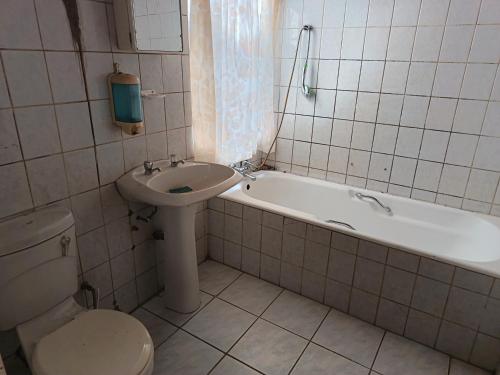 a bathroom with a sink and a toilet and a bath tub at Potch Guest Home in Potchefstroom