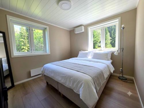 a bedroom with a large bed with two windows at Unique Villa by a beautiful lake in Omberg