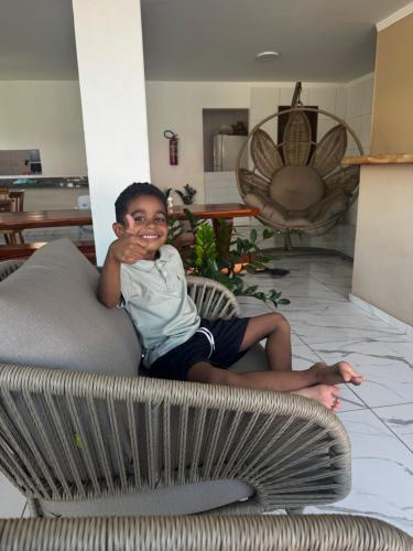 a young boy sitting on a couch in a living room at Pousada Vila Mar Japaratinga in Japaratinga