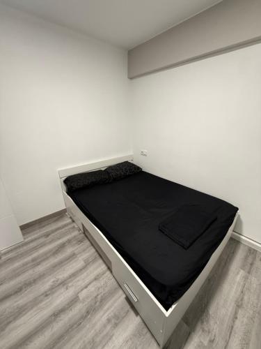 a bed in a white room with a black mattress at Alojamiento confort in Vigo