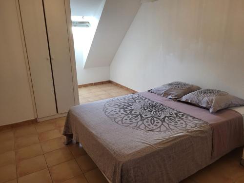 a bedroom with a bed with a purple blanket and pillows at Résidence les Antillannes in Gourbeyre