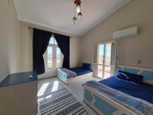 a bedroom with two beds and a window at Coastal Comforts at Casabianca in Dawwār Muḩammad Abū Shanab