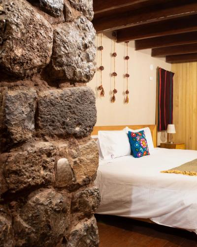 a bedroom with a stone wall and a bed at Casa Amará in Cusco