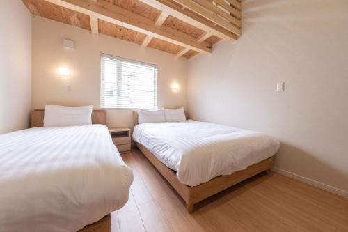 two beds in a small room with a window at Yukari B in Asahikawa