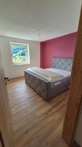 a bedroom with a bed and a pink wall at Hof am Berg in Kaunerberg