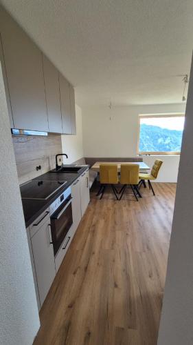 a kitchen with white cabinets and a table with yellow chairs at Hof am Berg in Kaunerberg